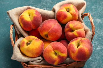 Wicker basket with sweet peaches on blue table