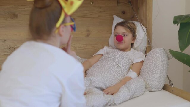 Medical sister with a red nose plays with a girl in her hospital ward