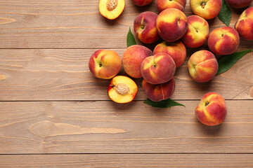 Many sweet peaches and leaves on wooden background