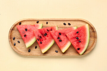 Board with pieces of fresh watermelon and seeds on beige background