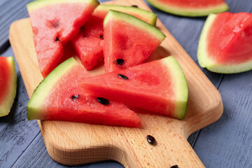 Board with pieces of fresh watermelon on blue wooden background