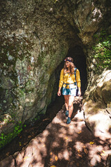 Tourist woman exiting a tunnel along an overgrown jungle trail next to a canal in Madeira rainforest. Levada of Caldeirão Verde, Madeira Island, Portugal, Europe.
