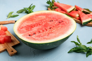 Half of fresh watermelon and boards with pieces on blue background