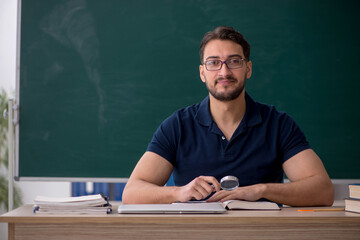 Young male teacher sitting in the classroom