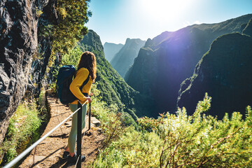 Backpacker woman enjoying scenic view from below large rock wall along water channel at steep cliff...