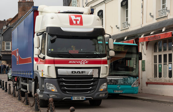 Honfleur northern France, Europe, 2023.  Driving on the left local bus passing a parked truck in a narrow street.
