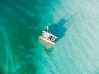 Drone shot showing a yacht in a large blue fresh water lagoon in Bacalar, Mexico. - obrazy, fototapety, plakaty