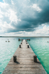 Wide shot showing pier leading to a fresh water blue lagoon in Bacalar, Mexico.