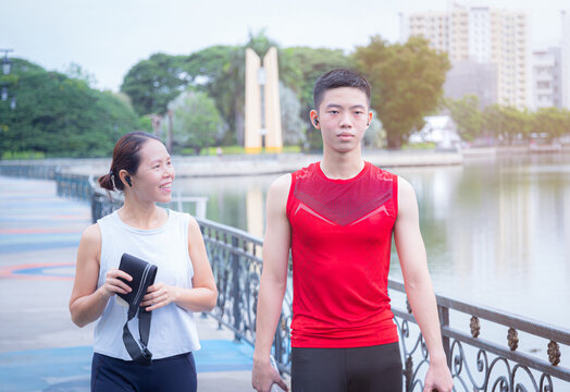 Mother and teenage son in workout clothes Go do outdoor exercise activities together. in the park. family fitness trends with jogging. Mother and daughter look at the camera while taking pictures.