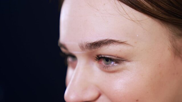Marking the lines for the future brow line with the help of a thread. White lines are drawn on the forehead of a client. Extreme close up.