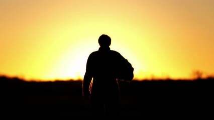 A Jet Pilot Walking holding His Flying Helmet at Air Base at Sunset. 4K Resolution.