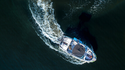 Aerial top view of a wake boat navigating the open river 