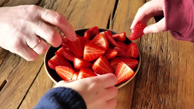 Hands take strawberries from a plate on a wooden table.Slow rotation. 4k footage