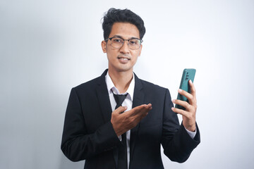 Portrait of a happy Asian young man wearing a suit while pointing at a mobile phone