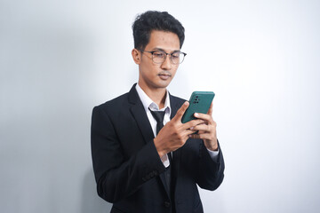 Photo of serious focused Asian man modern digital smart phone device, chats in social networks,