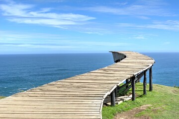 Photo of a picturesque wooden bridge stretching across a serene body of water in Chiloe, Chile