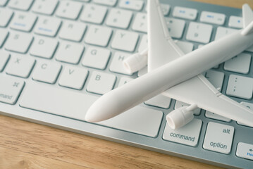 Airplane model on computer keyboard background. Booking flight tickets online concept. Search easy...