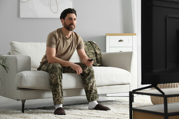 Soldier watching TV on sofa in living room. Military service