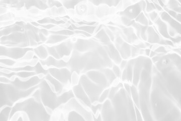Obraz premium White water with ripples on the surface. Defocus blurred transparent white colored clear calm water surface texture with splashes and bubbles. Water waves with shining pattern texture background.