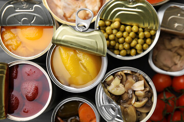 Open tin cans with different products as background, top view