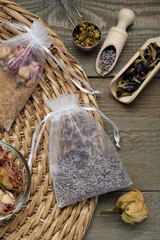 Scented sachets with dried flowers on wooden table, flat lay
