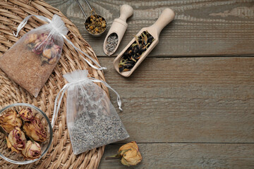 Scented sachets with dried flowers on wooden table, flat lay. Space for text - obrazy, fototapety, plakaty