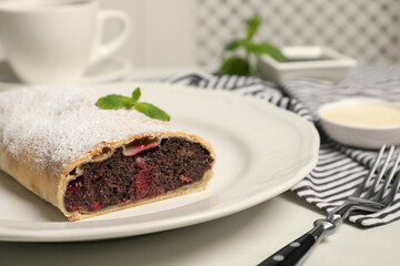 Delicious strudel with cherries and poppy seeds on white wooden table, closeup