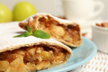 Delicious strudel with apples, nuts and raisins on wicker mat, closeup