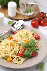 Plate of delicious pasta primavera served on white table, closeup