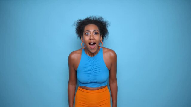 Black gorgeous model in blue top and yellow skirt smiles sweetly, presses hands to her cheecks and dances, good luck concept, copy space