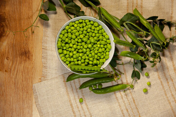 A bowl of appetizing green peas on a linen napkin. Top view.