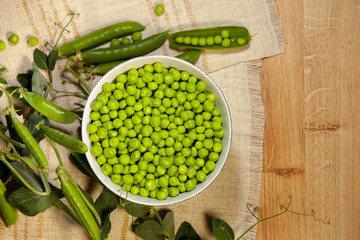 Green peas: beans in a bowl and pods on a napkin. Top view.