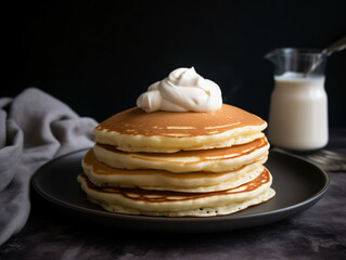 A stack of fluffy homemade pancakes topped with a drizzle of maple syrup and fresh fruit.