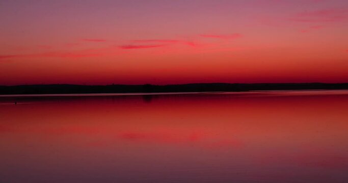 beautiful orange-yellow sunset on the lake in spring, the sun illuminates the lake with yellow-orange color at sunset