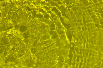 Yellow water with ripples on the surface. Defocus blurred transparent gold colored clear calm water...