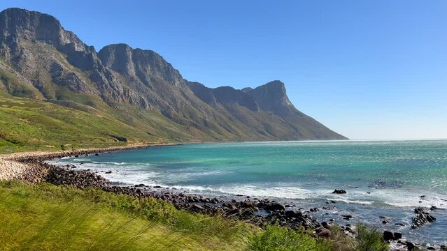 Koeel Bay Dappat Se Gat cinematic windy grass surf waves crashing stunning Kogel Bay Beach Cape Town South Africa coastline aqua deep blue water Gordon's Bay  Garden Route stunning pan left