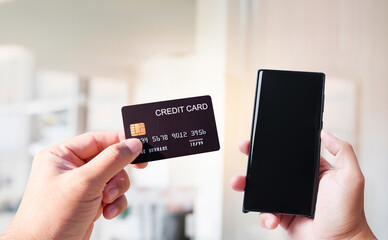 Hand holding a credit card and blank screen of mobile phone, online shopping concept.