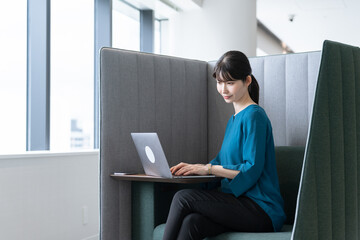 ボックス席でパソコンで仕事する女性