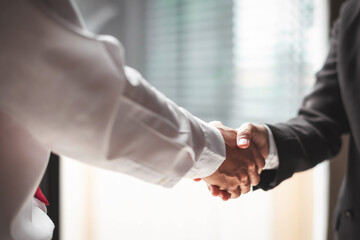 Close up of two business people shaking hands while sitting at the working place