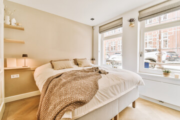 a bedroom with a bed, window, and lamp on the wall next to the bed is an open window that looks out onto the street