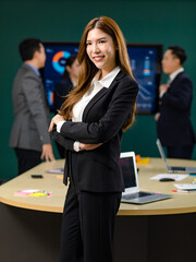 Portrait shot Millennial Asian professional successful businesswoman ceo entrepreneur in formal business suit standing crossed arms smiling in meeting room with male and female colleagues discussing