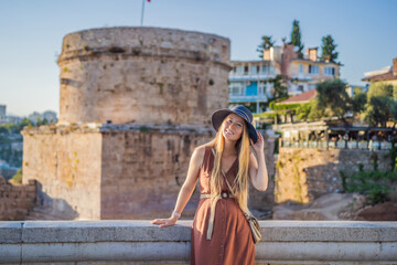 Woman tourist on background of Hidirlik Tower in Antalya against the backdrop of the Mediterranean bay of the ancient Kaleici district, Turkey. Turkiye