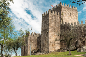Fototapeta na wymiar Guimaraes, Portugal. April 14, 2022: Walls and structures of Guimarães castle with blue sky.