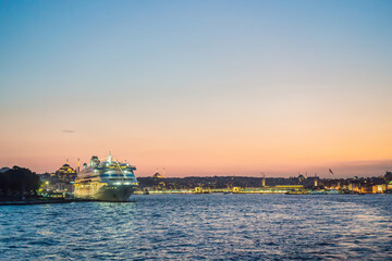 Fototapeta premium Istanbul at sunset, Turkey. Tourist boat sails on Golden Horn in summer. Beautiful sunny view of Istanbul waterfront with old mosque. Concept of travel, tourism and vacation in Istanbul and Turkey
