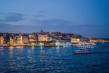 Istanbul at sunset, Turkey. Tourist boat sails on Golden Horn in summer. Beautiful sunny view of Istanbul waterfront with old mosque. Concept of travel, tourism and vacation in Istanbul and Turkey