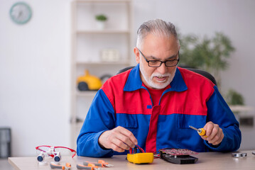 Old male repairman repairing computer