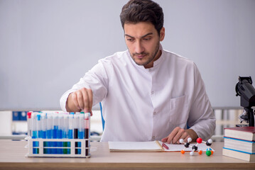 Young male chemist sitting in the classroom