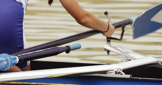 Close-up of the girl's hands fixing the oar to the clamping mechanism on the single scull