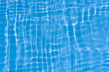 Blue water with ripples on the surface. Defocus blurred transparent blue colored clear calm water surface texture with splashes and bubbles. Water waves with shining pattern texture background.