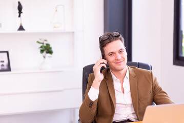 Businessman in brown suit color using mobile phone in modern office